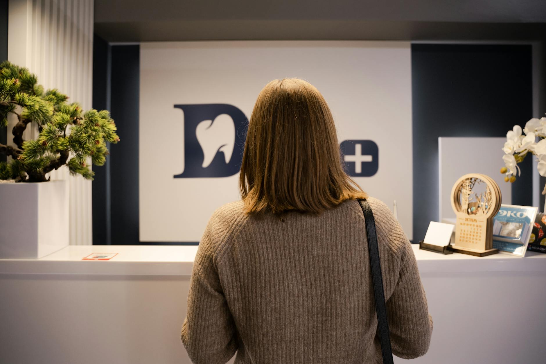 woman in brown sweater in front of a reception desk