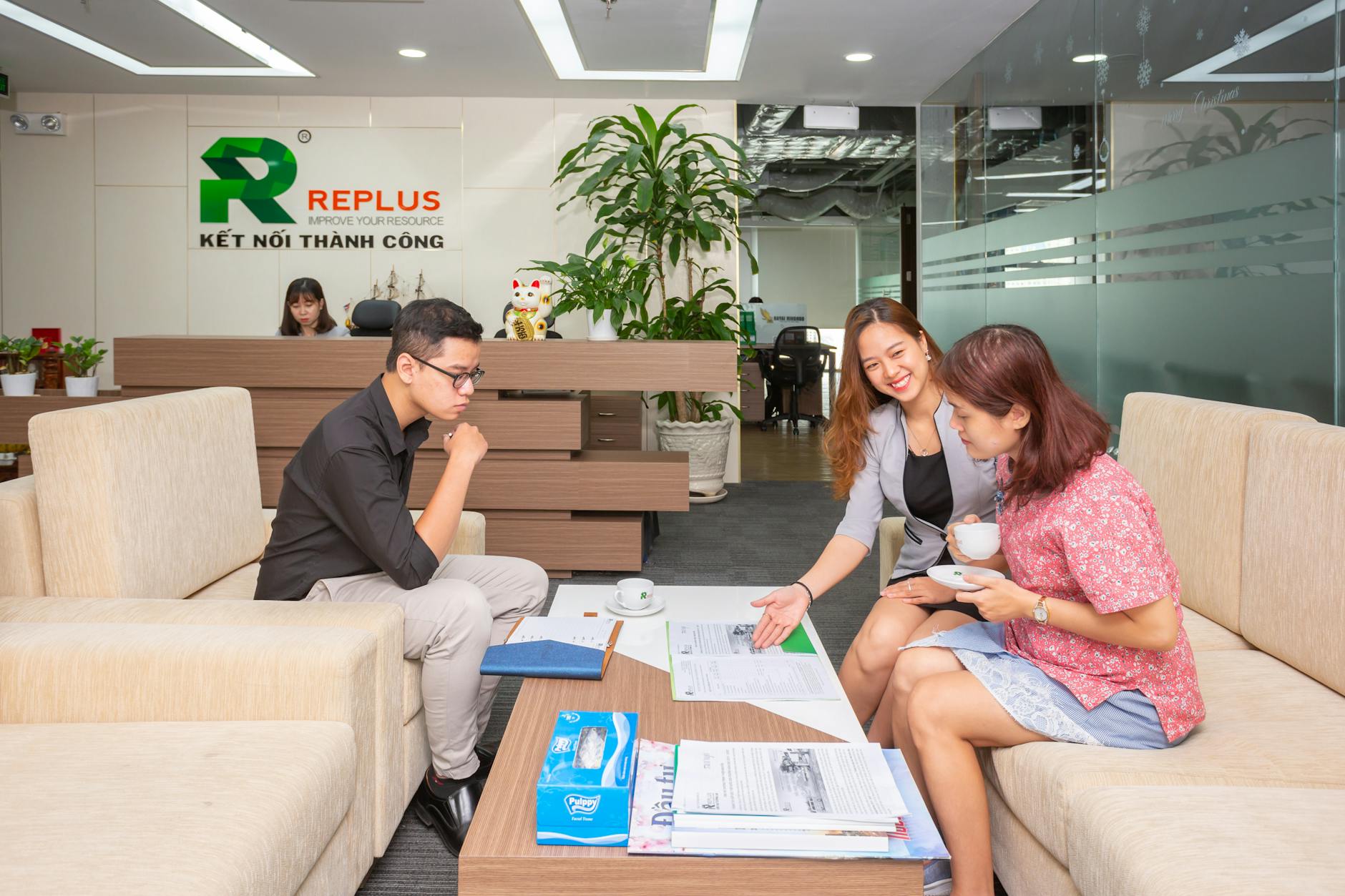 a consultant sitting at a table and talking to a man and woman in an office